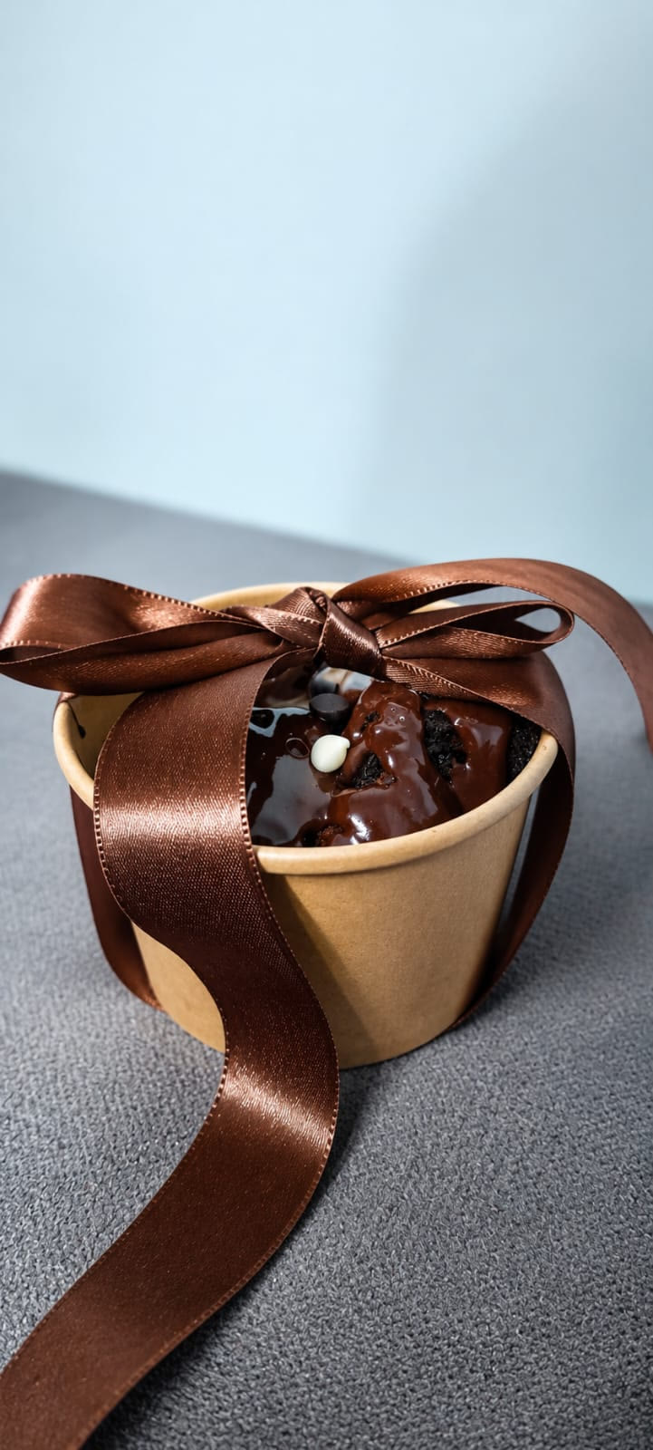 A kraft tub of saucy brownie tied with a brown ribbon